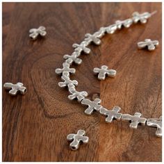 the cross necklace is made out of silver plated metal, and sits on a wooden surface