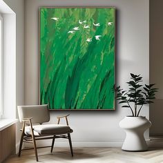 a painting hanging on the wall next to a chair and potted plant in a room