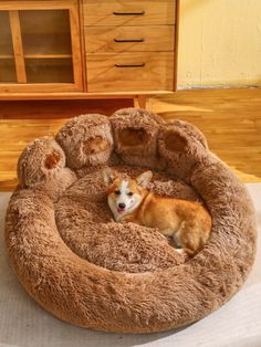 a small dog laying in a bed made out of teddy bear pillows on top of a table