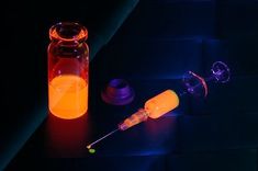 an orange liquid in a glass bottle next to a syringe