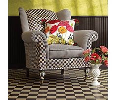 a chair and vase with flowers on a checkered floor