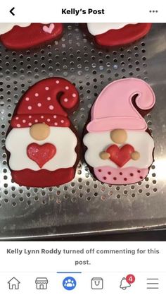 three decorated cookies sitting on top of a metal tray with hearts and gnomes in the middle