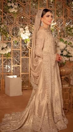 a woman in a wedding dress standing next to a flower arrangement and wearing a veil