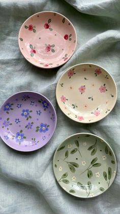 three plates with flowers painted on them sitting on a bed