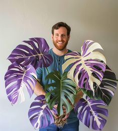 a man holding a large purple and white plant