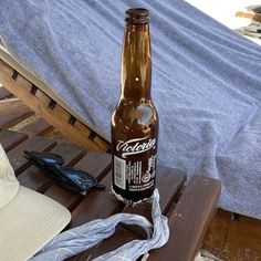 a bottle of beer sitting on top of a wooden table next to a blue towel