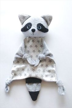 a stuffed raccoon laying on top of a white surface with stars around it