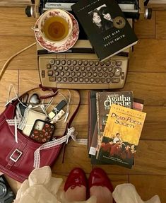 there are many books and other items on the floor next to an old typewriter