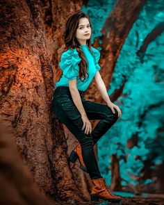 a woman is sitting on a tree and posing for the camera