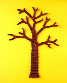 a crocheted tree is shown on a yellow background, with the shape of a leafless tree