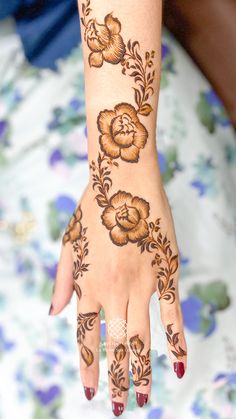 a woman's hand with henna on it and flowers painted on the palm