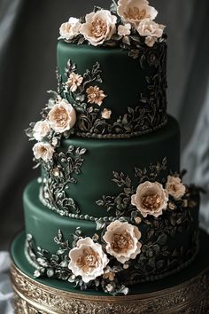 a three tiered green wedding cake with white flowers on the top and gold trimmings