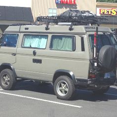 an suv parked in front of a pet shop on the side of the road with luggage strapped to it's roof