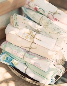 a stack of folded cloths sitting on top of a wooden table next to a window