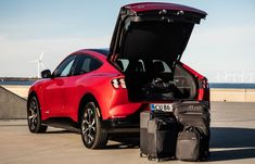 a red car with its trunk open and luggage in front