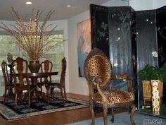 a dinning room table and chairs in front of a black screen with leopard print on it