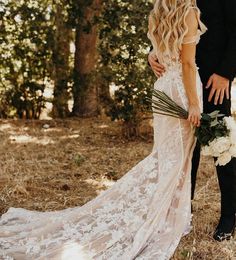 a bride and groom are standing in the woods holding each other's bouquets