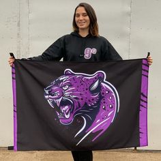 a woman holding up a purple and black banner with a tiger on it's side