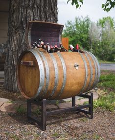 an old wooden barrel with tools in it sitting next to a tree