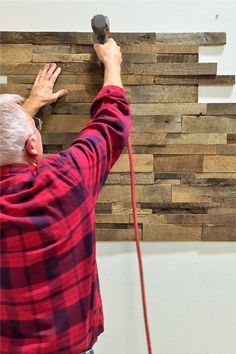 an older man is working on a wood paneled wall with his hand held in the air