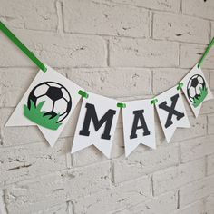 a banner with soccer balls and the word max on it hanging from a brick wall