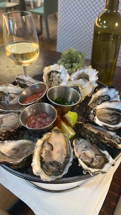 a platter of oysters with wine and condiments on the side at a restaurant