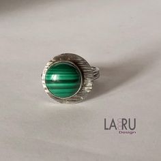 Make a statement with this unique malachite sterling silver ring. The circular Cabochon has distinct horizontal stripes in shades of green and black. Size 10 US The stone is set on a circular border plate with horizontal textured grooves. The fine silver bezel is purposely off center, having the border plate centered over your finger while stone offset to one side in an asymmetrical celestial design. 😊Please visit my shop @ https://www.larudesign.etsy.com Modern Green Malachite Jewelry, Green Malachite Rings With Polished Finish, Malachite Ring, Celestial Design, Malachite Rings, Handmade Sterling Silver Rings, Horizontal Stripes, Size 10 Rings, Green Stone