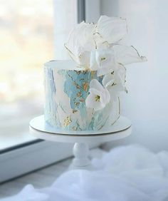 a white and blue cake with flowers on top