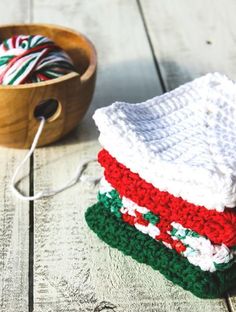 two crocheted dishcloths sitting next to a wooden bowl