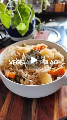 a bowl filled with rice and vegetables on top of a wooden cutting board next to a potted plant