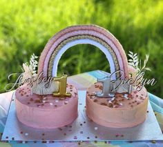 there are two cakes with pink frosting and gold decorations on them, one is shaped like a rainbow