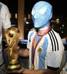 a man in a spider mask holding a soccer trophy