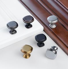 an assortment of knobs and pulls on a white surface with wood grained edges