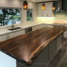 a kitchen with an island made out of wood in the center and two pendant lights hanging from the ceiling