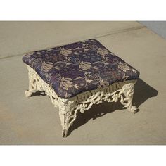 a bench with a blue and white flower pattern on the seat is sitting on concrete