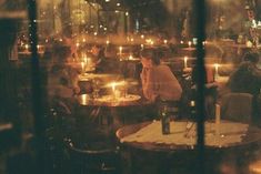 people sitting at tables in a restaurant with candles lit