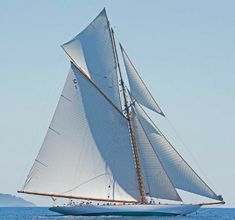 a sailboat with white sails sailing in the ocean