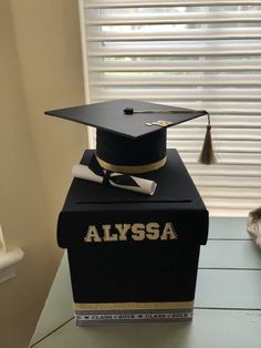 a graduation cap and diploma sitting on top of a black box that says alyssa