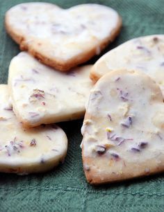 several heart shaped cookies with white frosting on a green cloth