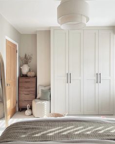 a bedroom with white closets and beige bedding