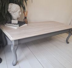 a wooden table with two books on it and a plant in the corner next to it