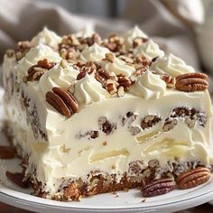 a piece of cake with white frosting and pecans on top