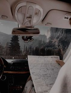 a man sitting in the passenger seat of a car reading a map