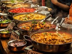 many different types of food are on display at a buffet table with price tags and signs