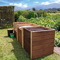 three wooden planters in the middle of a garden