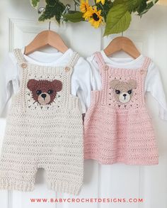 two crocheted baby rompers hanging on a door with flowers in the background