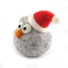 an owl wearing a santa hat on top of a gray ball with googly eyes