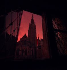 the reflection of an old building in a window at night with red sky and clouds