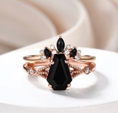 a black diamond ring sitting on top of a white table next to a stack of rings