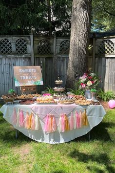 a table that has some food on it in the grass near a tree and fence